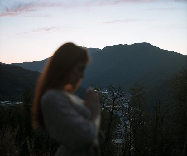 Person meditating peacefully outdoors with a sunset in the background.